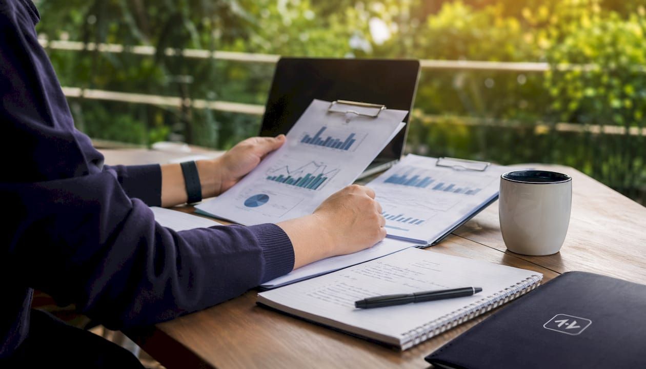Hands analyzing financial charts on glass table