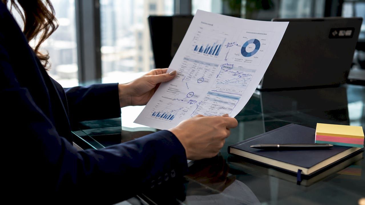 Hands holding market forecast with notes overhead