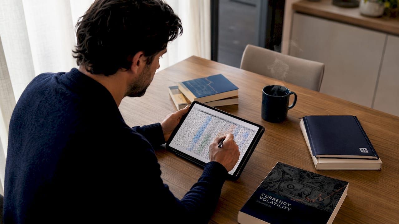 Hands scrolling forex volatility data on laptop